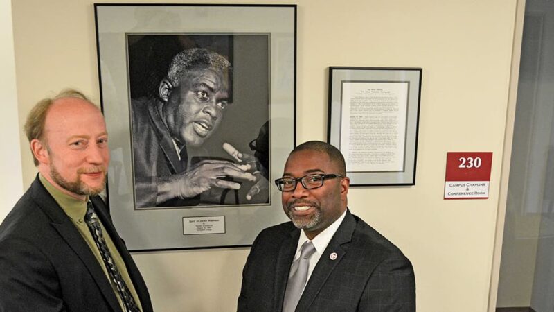 Marty Dobrow, left, and Calvin Hill stand by a photo of the late Jackie Robinson.
